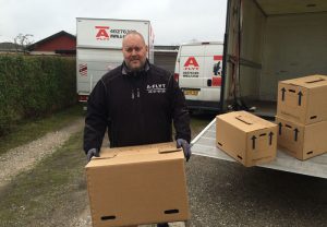 Man d flytter en flyttekasse ud af en flyttebil